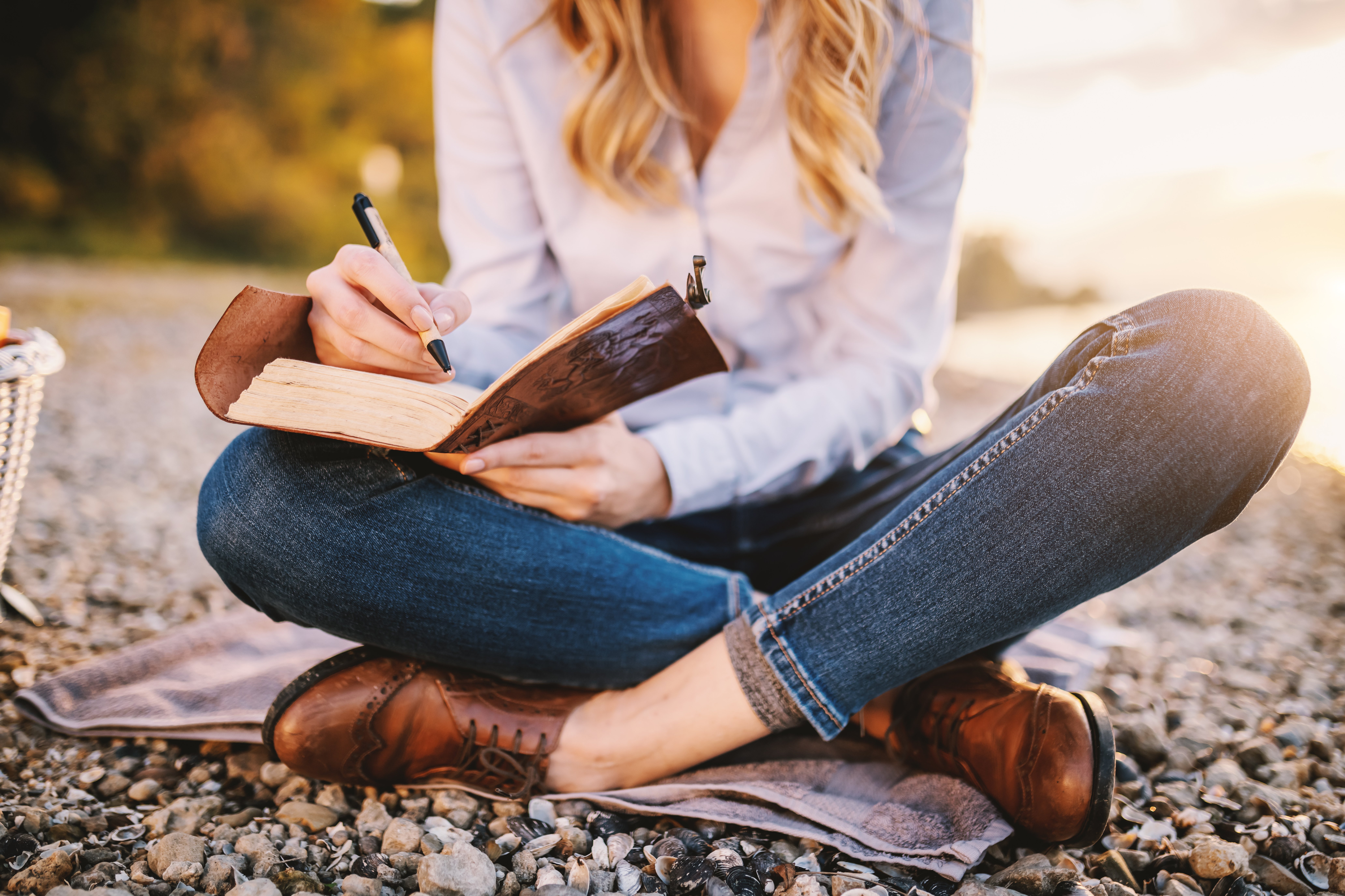 person sitting on the ground and writing in journal