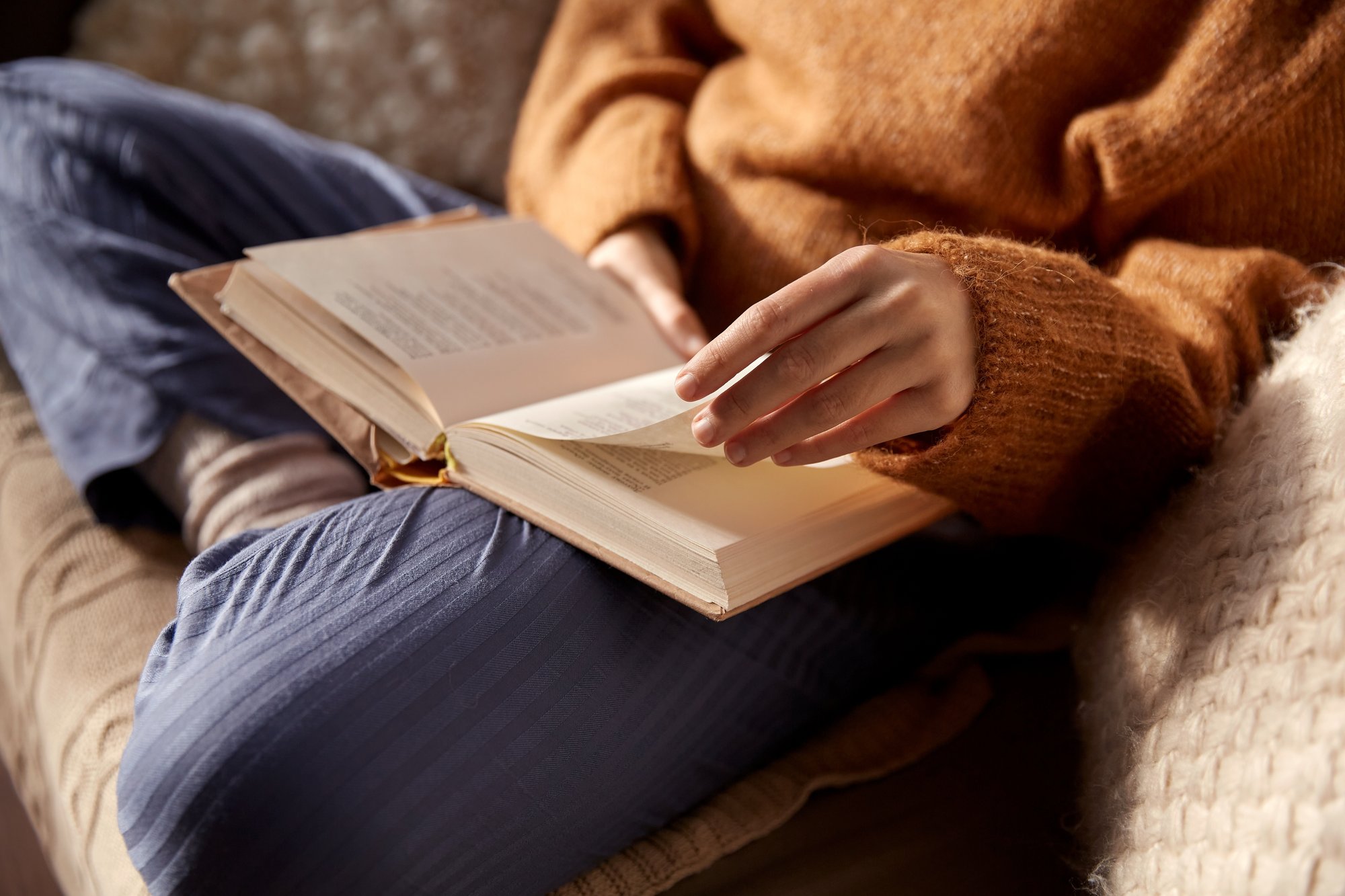 person holding and reading a book in their lap