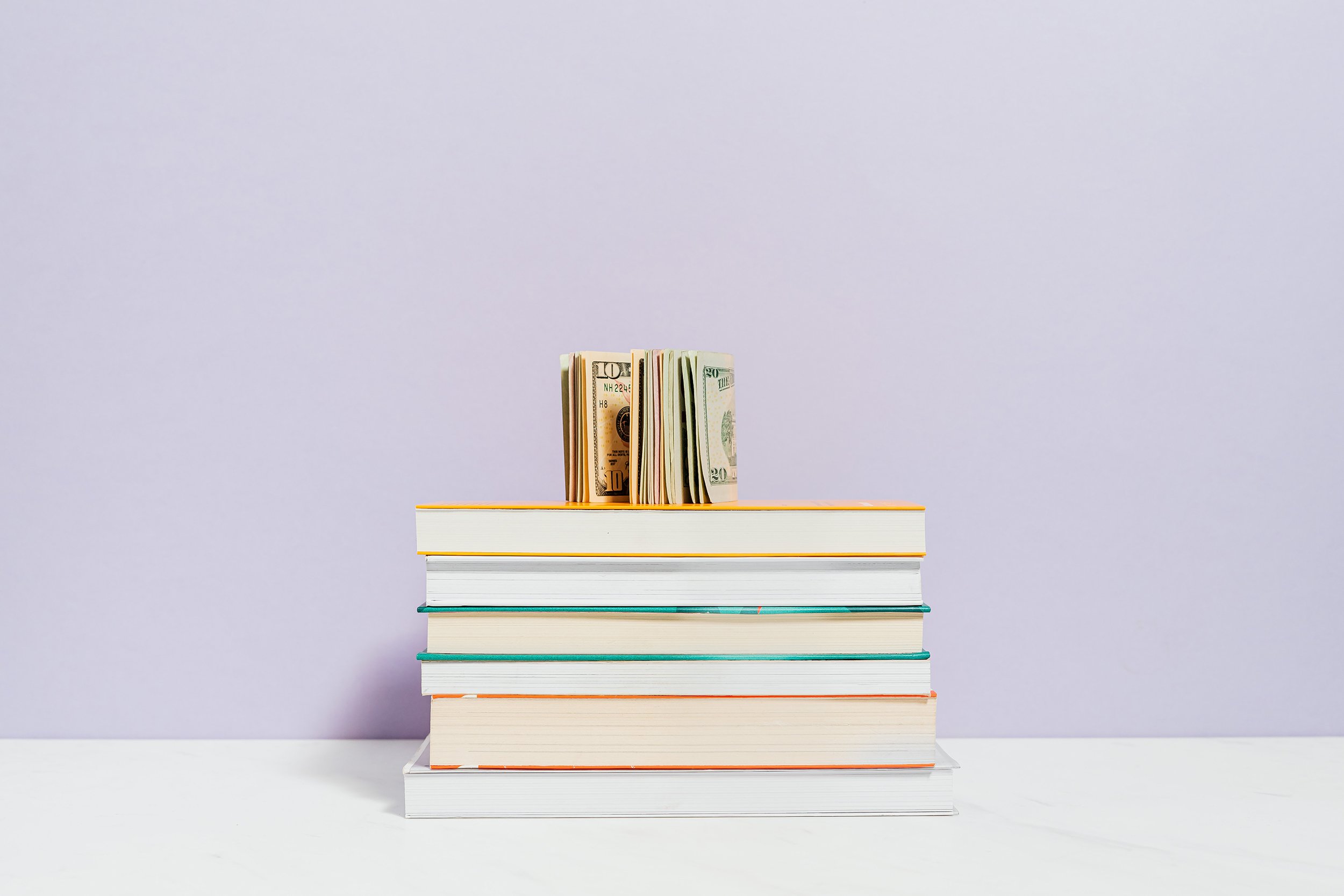 Dollar bills on book pile