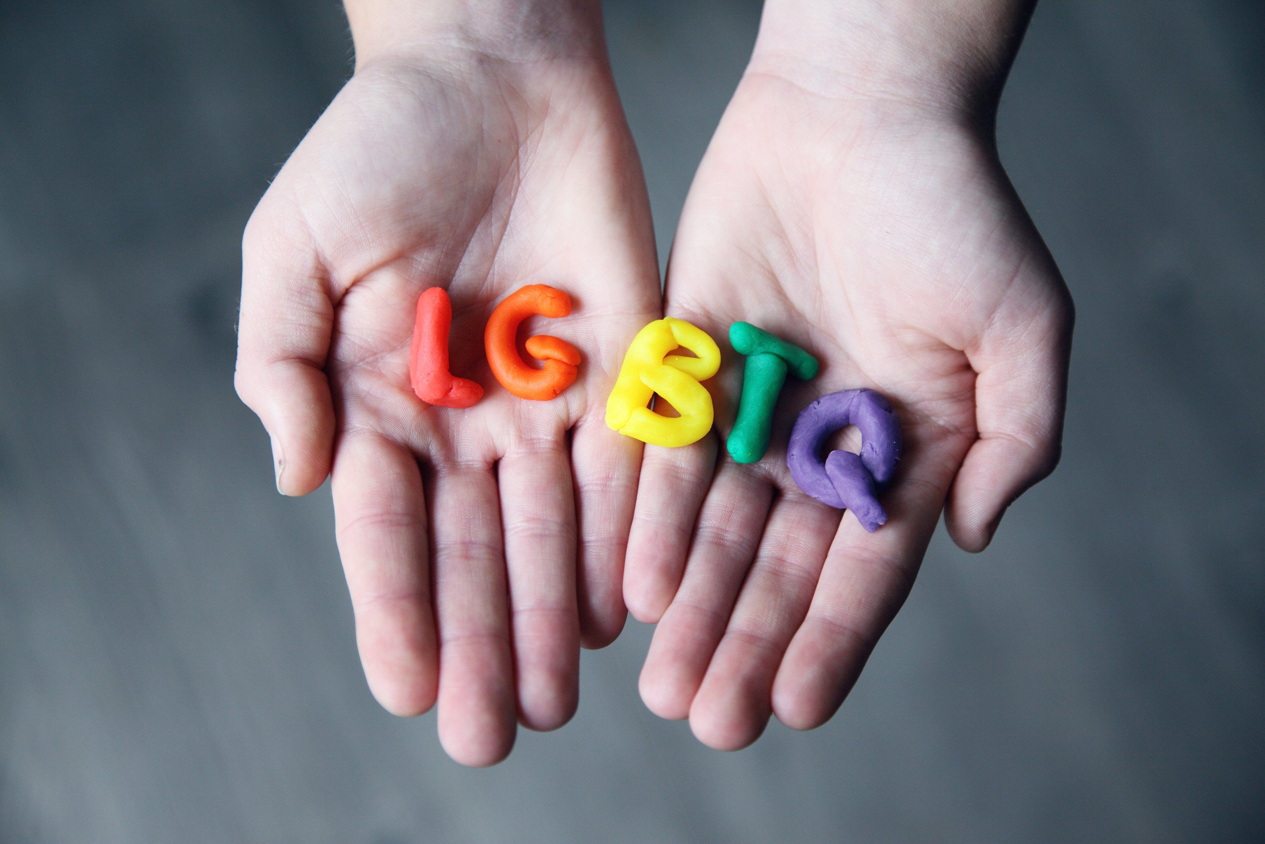 Hands holding LGBTQ letters