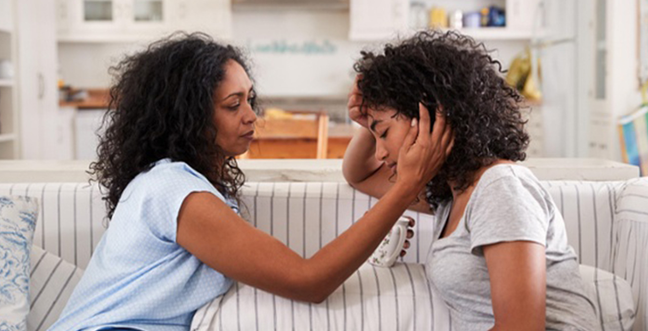 Mother comforting her daughter by holding her cheek in the palm of her hand.