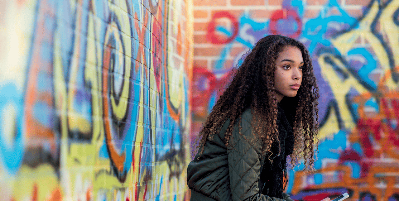 teen girl staring out in front of a graffiti wall