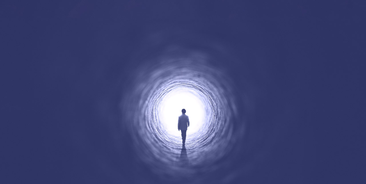Person walking through a dark tunnel into the light
