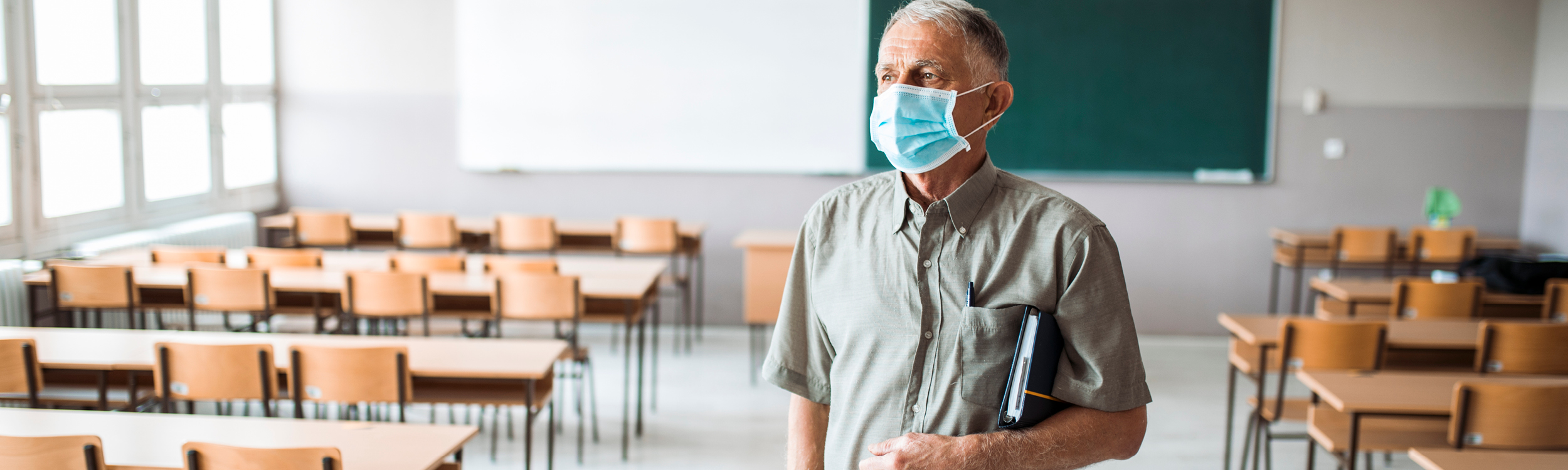 Educator wearing mask in empty classroom