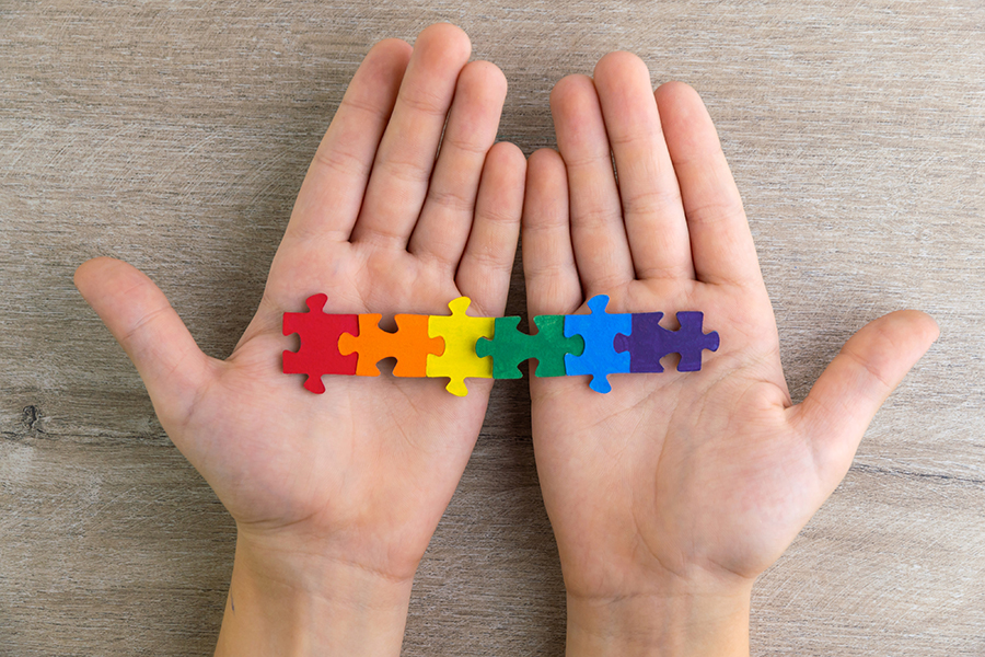hands holding rainbow puzzle pieces
