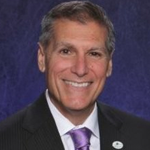Headshot of gentleman with purple tie in a suit